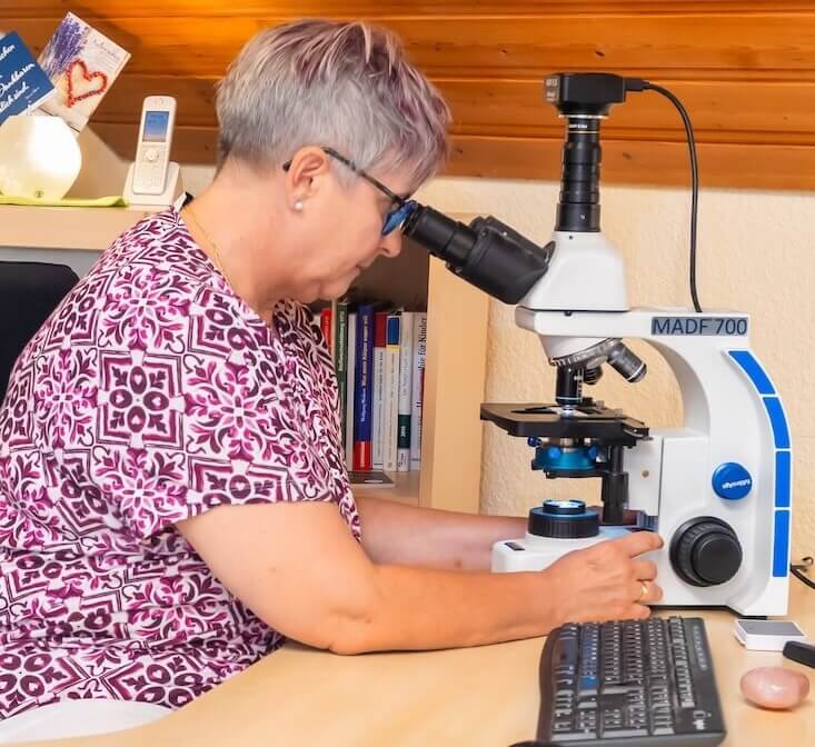 Heilpraktikerin Angelika Maria Zimmermann bei der Dunkelfelddiagnose in ihrer Praxis in Ettringen. Sie untersucht konzentriert einen Blutstropfen unter dem Mikroskop.
